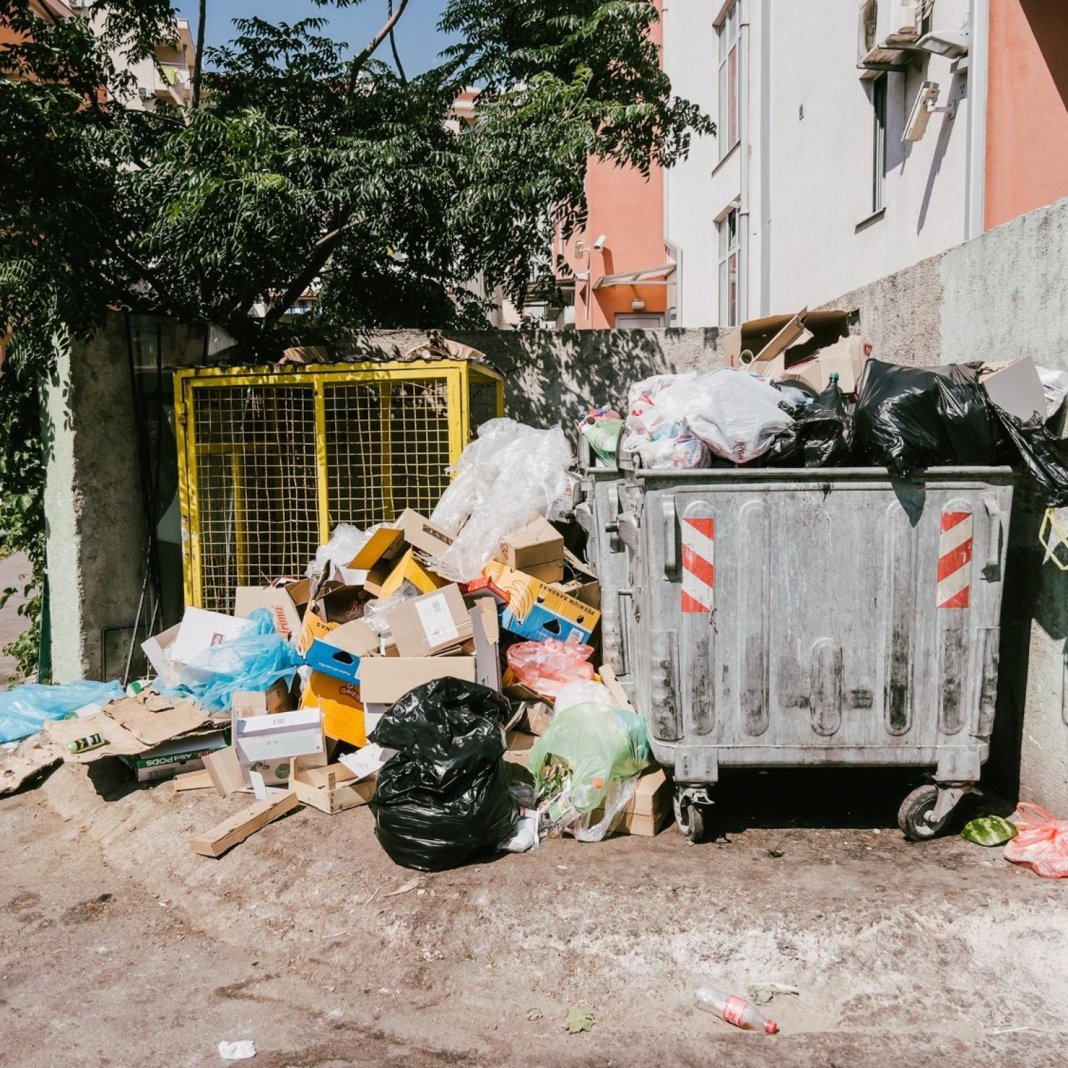 garbage-is-piled-overflowing-dumpster-near-highrise-building