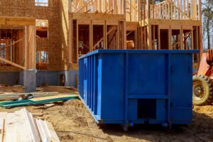 a rented blue Junk It garbage bin outside an ongoing house roof renovation to be used as garbage bin for the roof debris and other construction waste