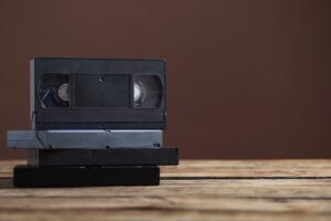 piled up old videotapes on and old wooden table that is not worth keeping