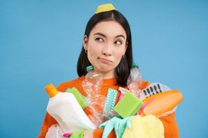 portrait of an asian woman with empty plastic bottles looks aside thinkin to recycle garbage or renting a garbage bin