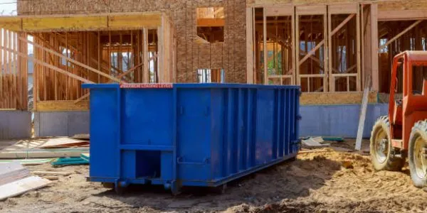 a blue dumpster bin near construction - Junk It offering reliable construction dumpster rental in Canada