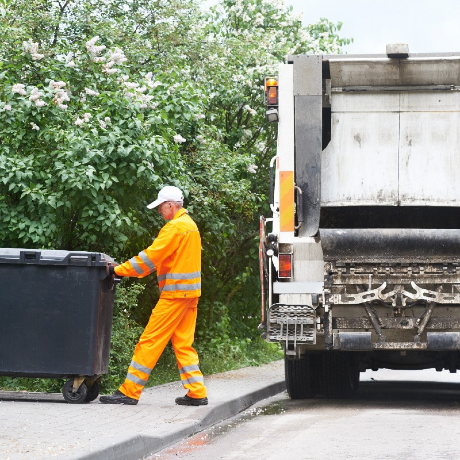 a Junk It bin rental service staff pulling a garbage bin into the dumpster truck