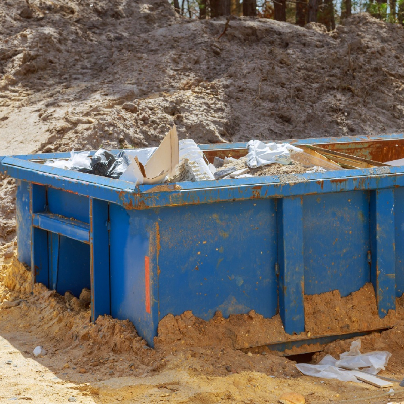 a blue Junk It dumpster bin loaded with construction trash from a renovated house
