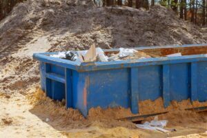 a blue Junk It dumpster bin loaded with construction trash from a renovated house