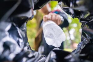 man-throws-garbage-into-garbage-can-street-with-worm-view-from-inside-trash-bin-to-avoid-illegal-dumping