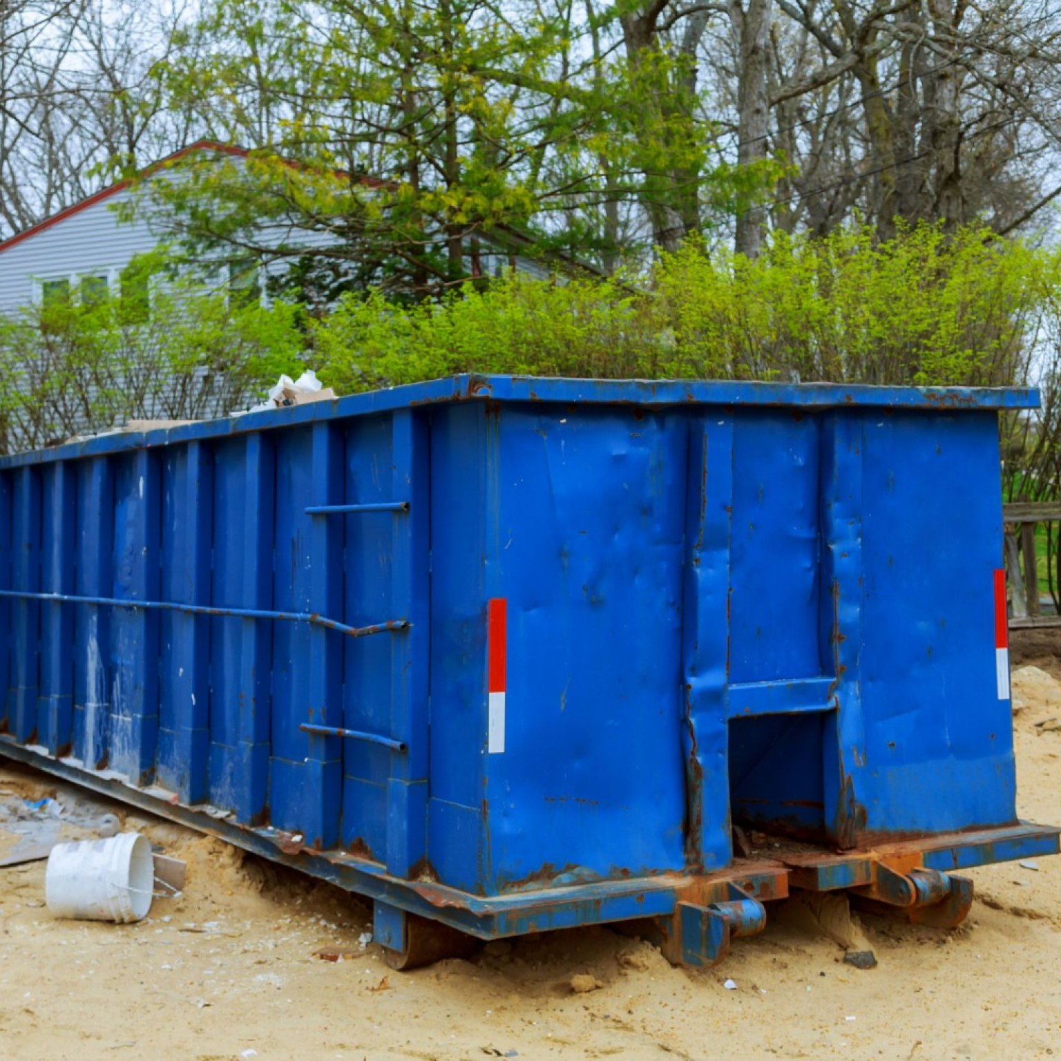 blue Junk It dumpster bin near the residential area for a dumpster near me