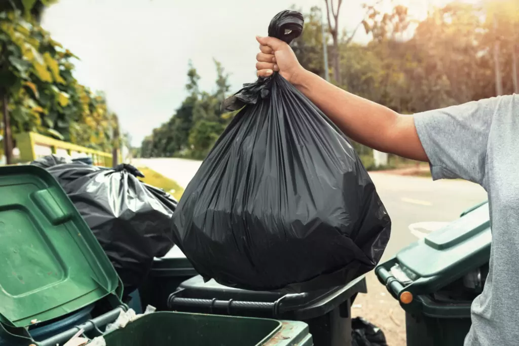 Woman holding a black garbage bag - ready to dispose of unwanted items with reliable garbage bin rental in Toronto