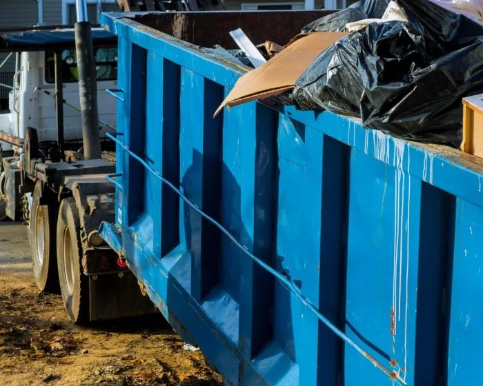 Junk It truck hauling a garbage bin full of garbage - providing efficient garbage bin rental in Scarborough for your waste removal need
