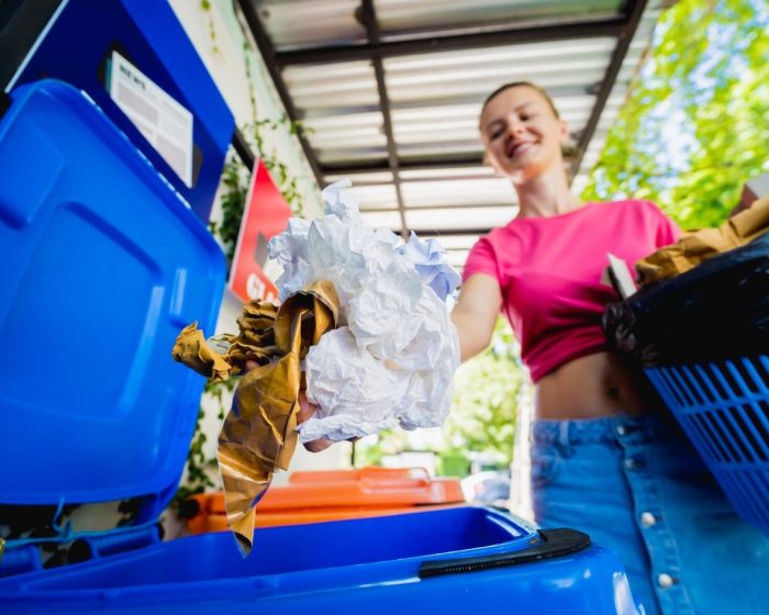 A young, beautiful girl throwing sorted garbage into special bins. Make your disposal easy with bin rental services in Brampton
