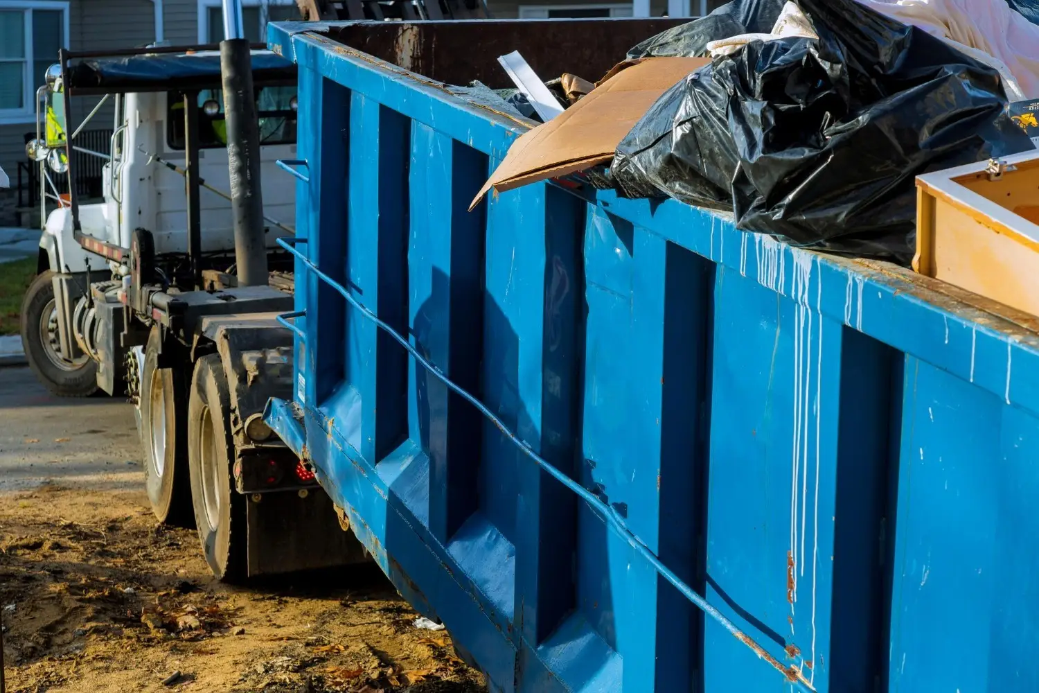a truck picking up the loaded blue garbage bin - make waste disposal easy—book bin rental services in Calgary today