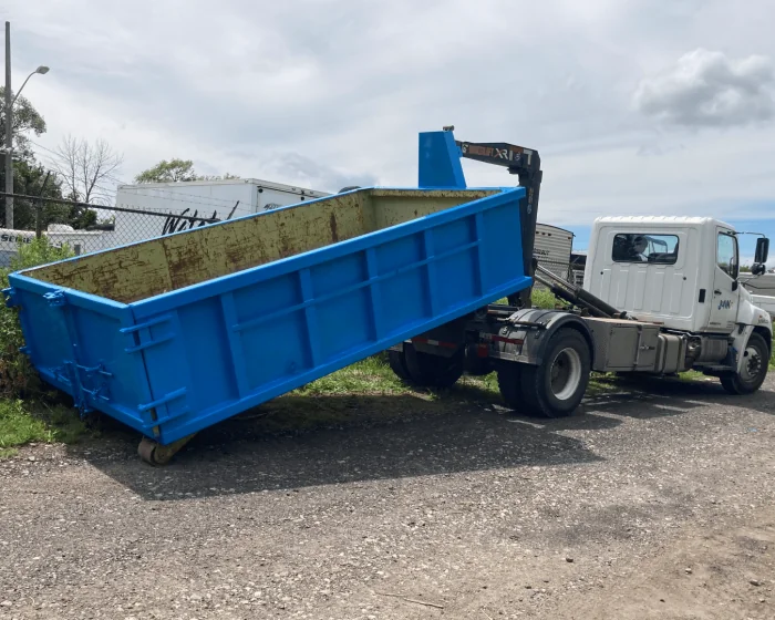 A white truck delivering a rented Junk It garbage bin - offering reliable garbage bin rental in Vancouver for your waste management needs