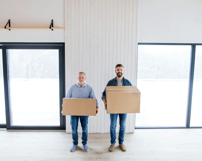Two men holding boxes in a room, preparing to clear out clutter with efficient garbage bin rental in Scarborough