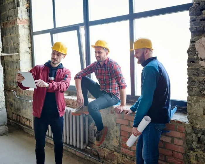 three construction men looking at a tablet, planning their next steps - for efficient waste disposal, consider bin rental in Cambridge
