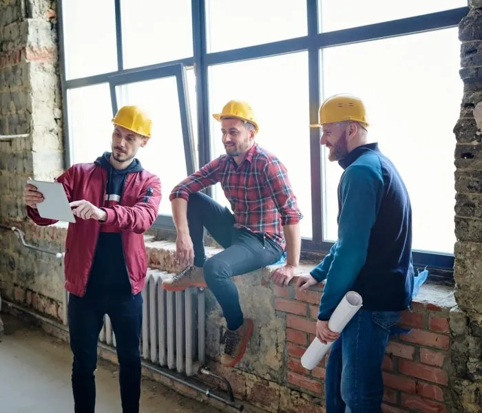 Three construction men looking at a tablet - possibly discussing the best options for garbage bin rental in Vancouver to manage their construction site waste efficiently