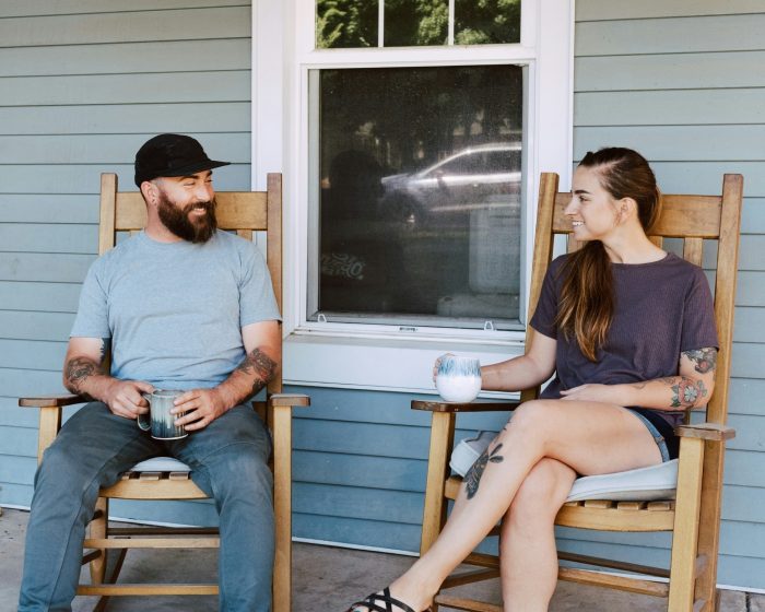 Two people sitting on individual rocking chairs by a porch - enjoying their time while considering hassle-free garbage bin rental in Scarborough for their waste disposal needs