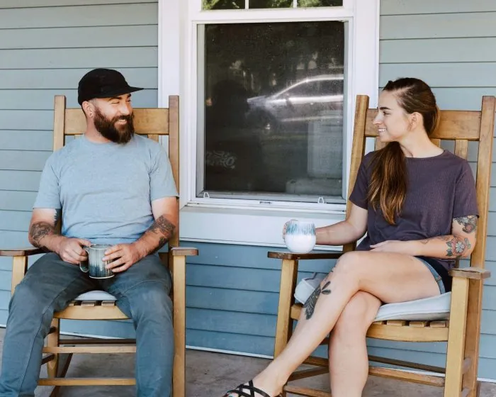 man and woman sitting while holding a glass and talking - discussing how garbage bin rental in Richmond Hill can simplify their waste management needs