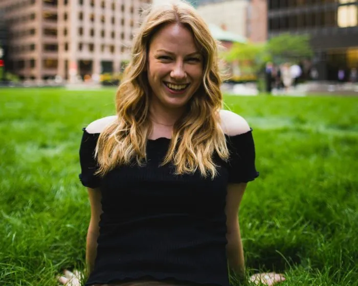 blonde woman in a black off-shoulder outfit smiling - ready to make the most of hassle-free garbage bin rental in Richmond Hill for all her waste disposal needs