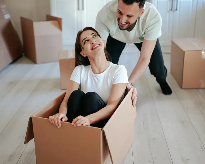 a man and woman in a box - a happy couple organizing - they used Junk It in Cambridge garbage bin rental services