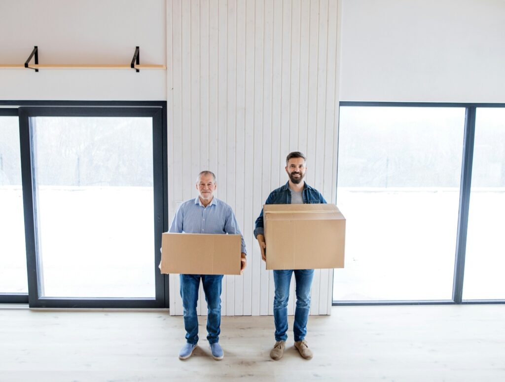 Two men holding boxes in a room - preparing to declutter with garbage bin rental in Toronto for easy disposal