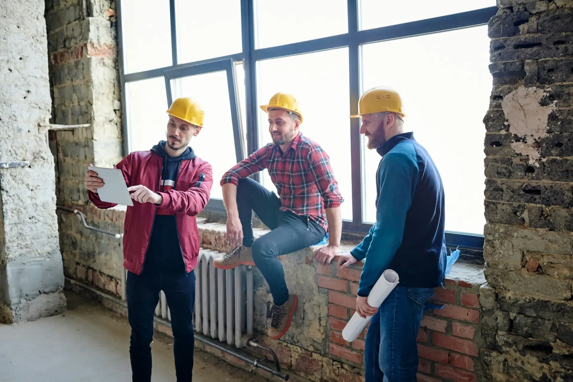Three construction men looking at a tablet, planning their next project with the help of efficient bin rental in Kitchener for waste disposal