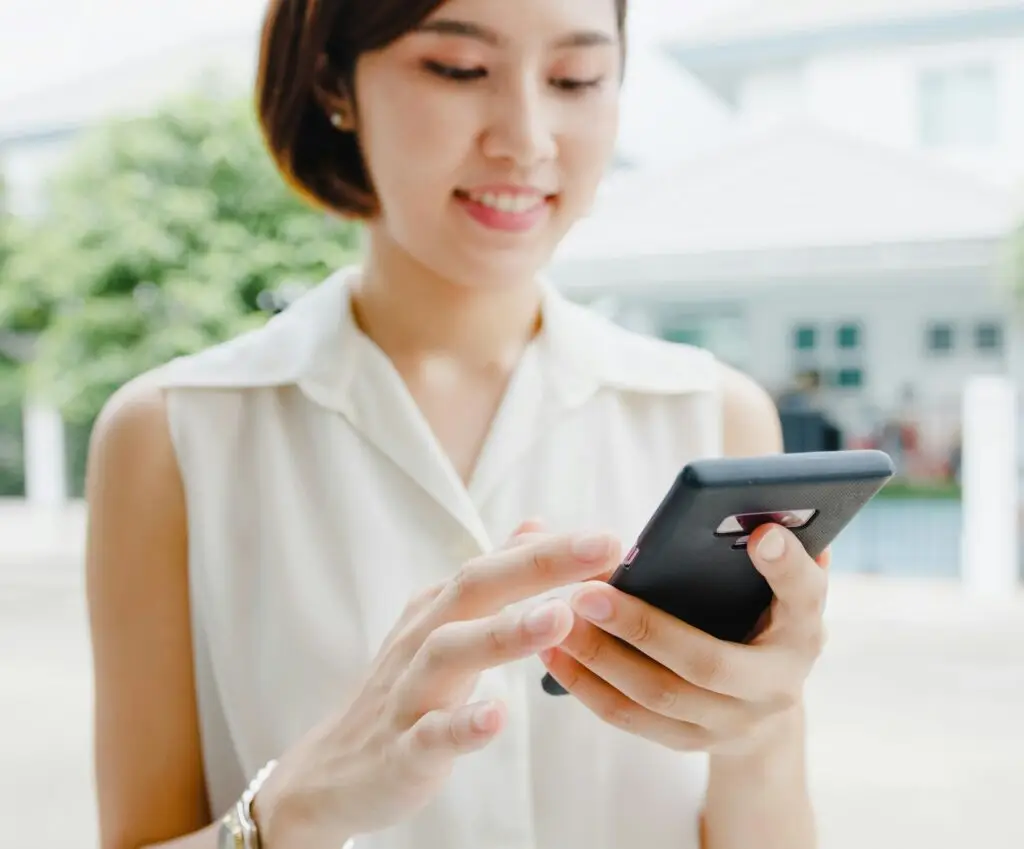 Woman looking at her black phone - considering how Junk It’s garbage bin rental in Toronto can simplify her waste disposal needs