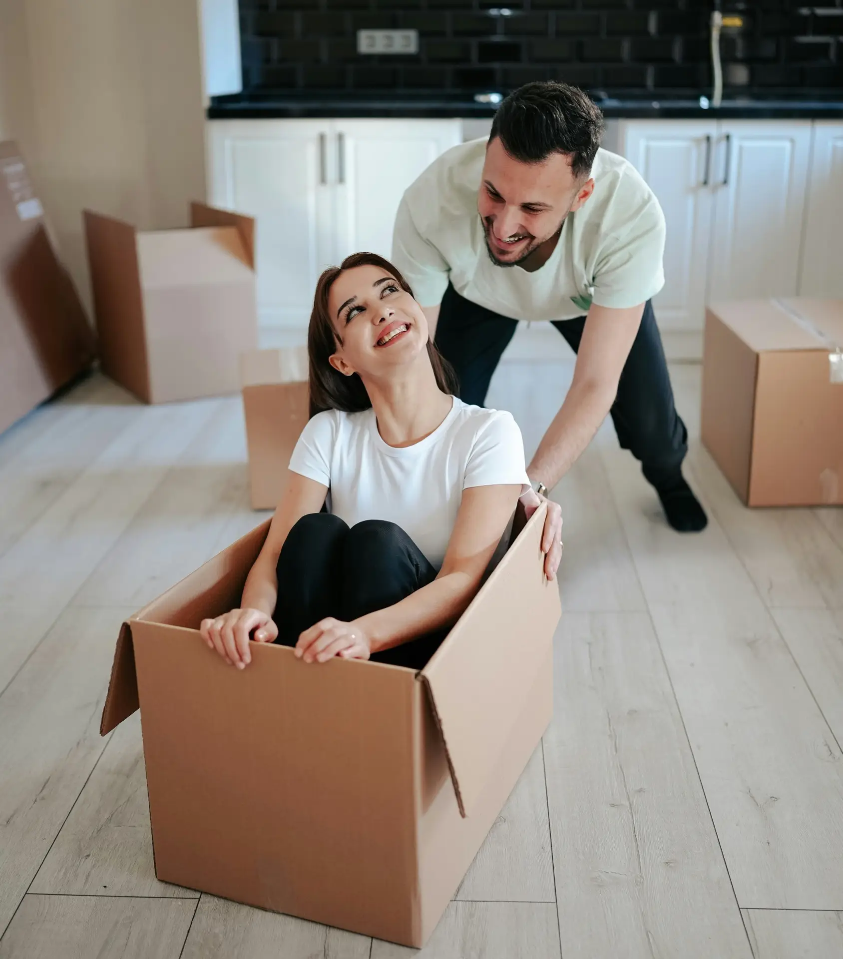 a man and woman in a box - a happy couple organizing - they used junk it in Kitchener garbage bin rental services for their garbage removal needs