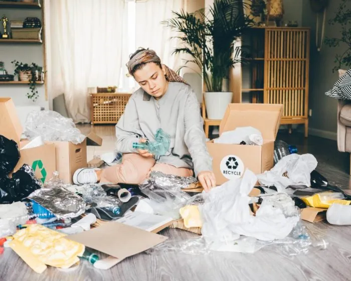 A woman sitting on the floor surrounded by junk and clutter - thinking about how garbage bin rental in North York can help her clear the mess effortlessly