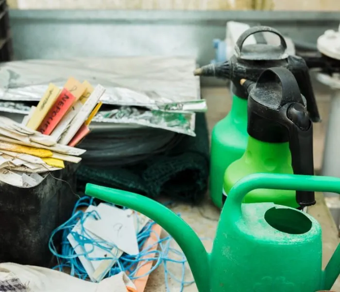 A pile of old watering cans and garden signs inside a cart - perfect for clearing out with garbage bin rental in Vancouver